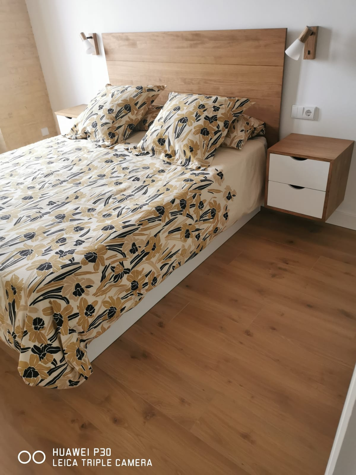 Cabecero de madera maciza y mesitas de noche con frentes blancos instalados en un dormitorio