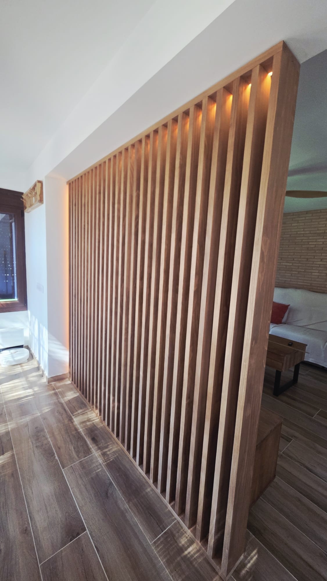 Vista trasera del separador de madera maciza con listones de 11 por 4 cm e iluminación LED encendida